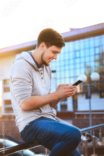 Portrait of a young man in casual clothes with a phone on the background of the business center. The informal business, free business concept