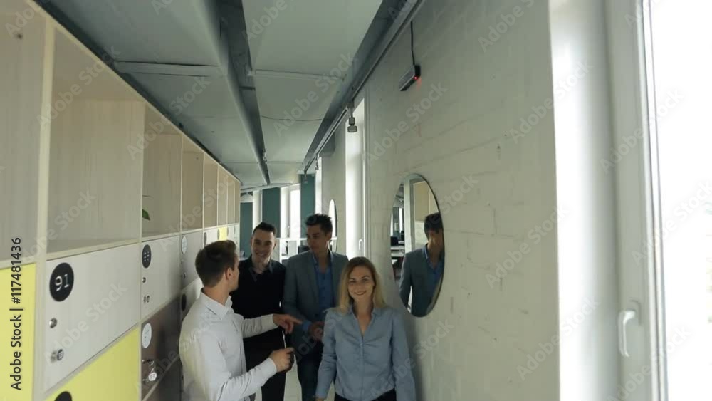 Young men and women praise each other and hug walking down hallway of office. Young men and women praise each other and hug walking down hallway of office.