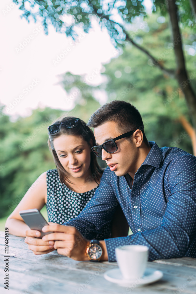 Young couple at cafe looking at mobile phone Young couple at cafe looking at mobile phone