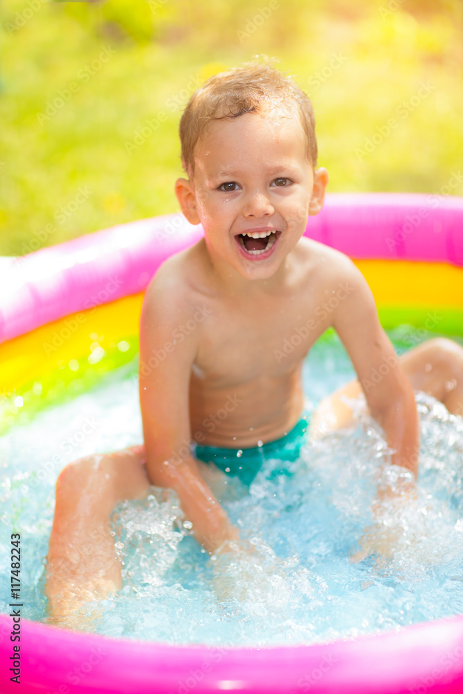 Little boy in inflatable swimming pool outdoor, having fun Little boy in inflatable swimming pool outdoor, having fun