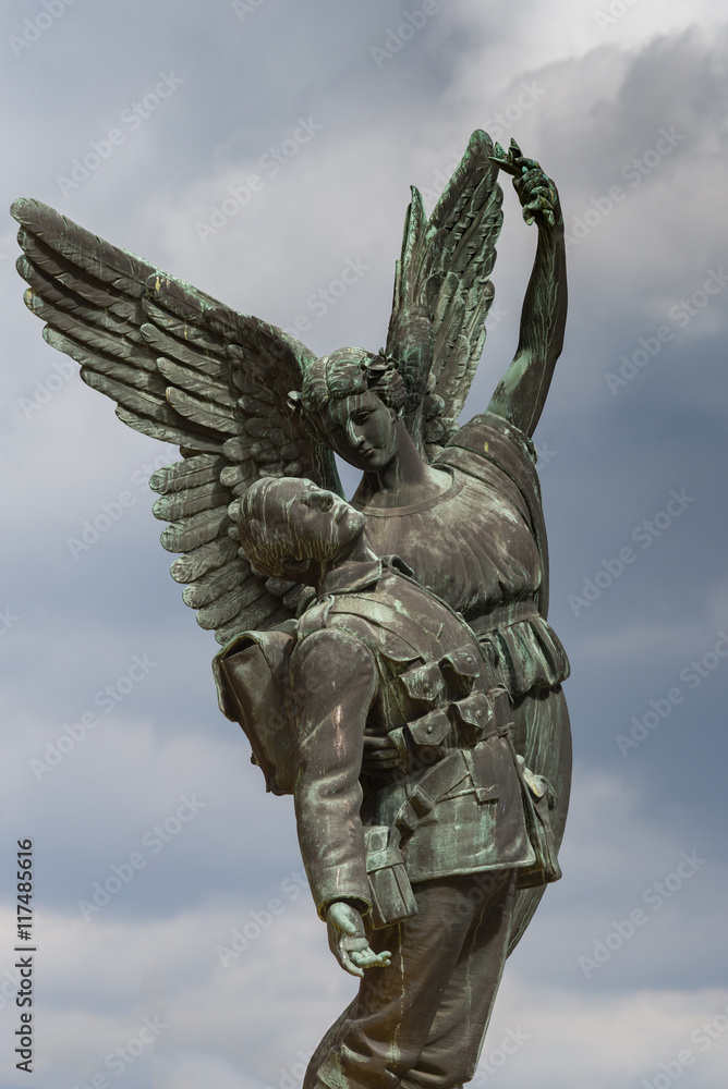 Vancouver, Canada - July 23, 2016: Bronze statue of angel carrying dead soldier to skies. Commemorates Canadian Pacific Railway workers who died in WW I and WW II. Only background mixed colored sky.