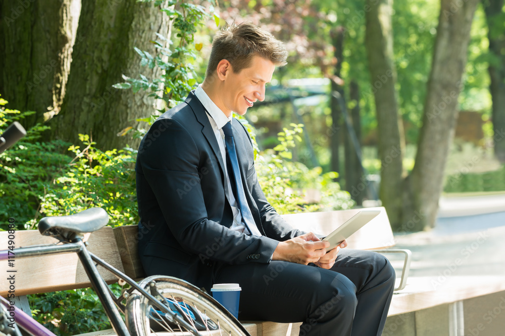 Businessman Sitting On Bench Using Digital Tablet Businessman Sitting On Bench Using Digital Tablet
