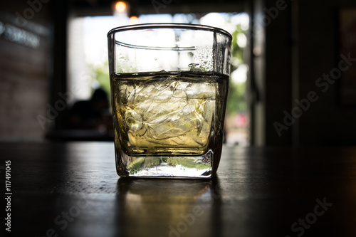 a cup of ice tea on wooden table,dark light style