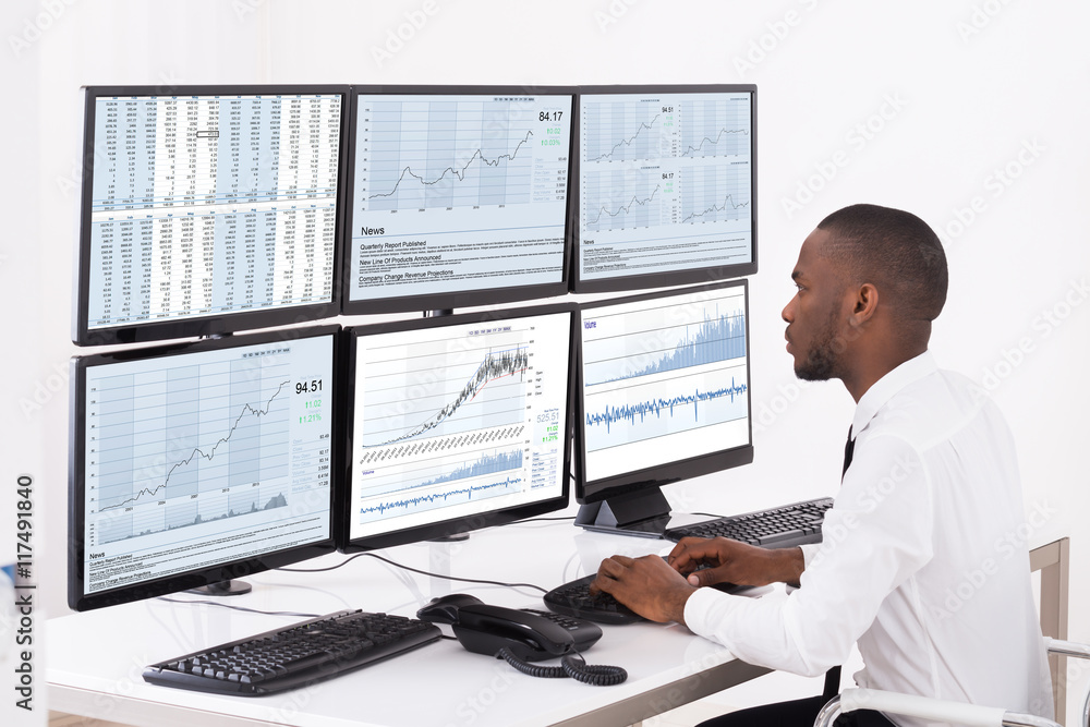 Stock Market Broker Looking At Graphs On Multiple Computer Stock Market Broker Looking At Graphs On Multiple Computer