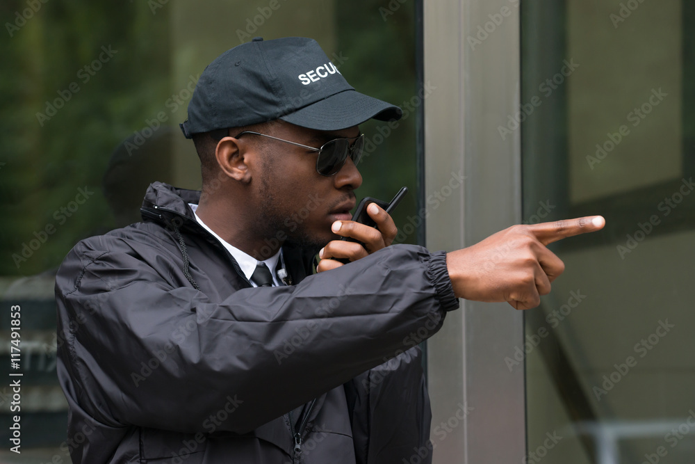 Male Security Guard Talking On Walkie-Talkie Photos | Adobe Stock