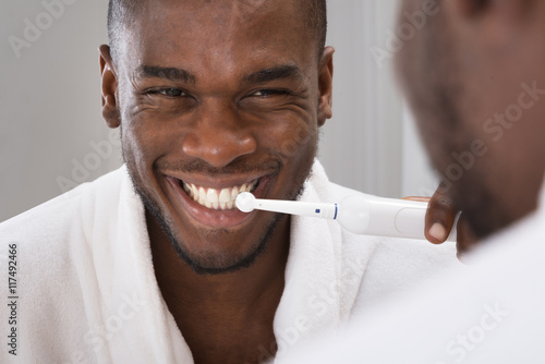 African Man Cleaning His Teeth In Front Of Mirror