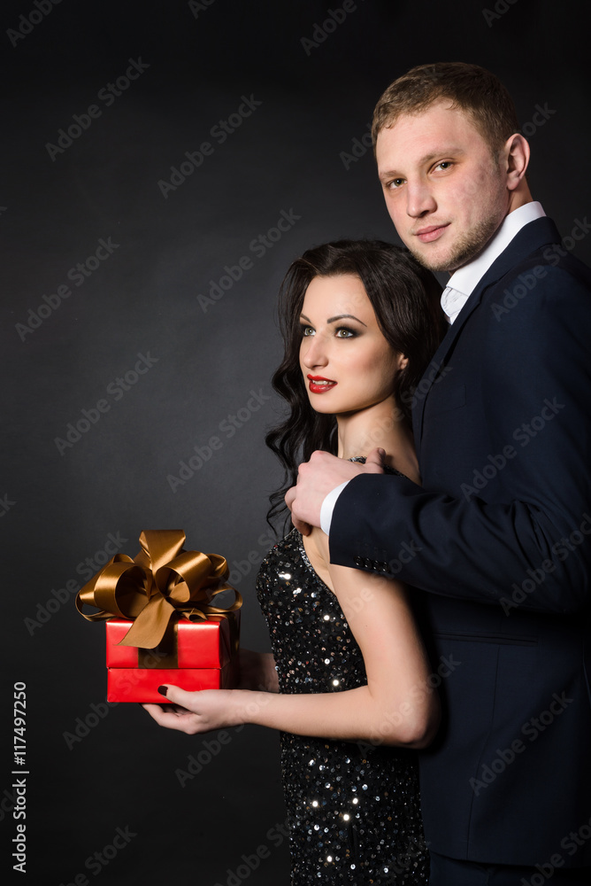 Elegant man and woman with red gift box on black background Elegant man and woman with red gift box on black background