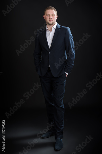 Portrait of handsome stylish man in elegant suit on black background