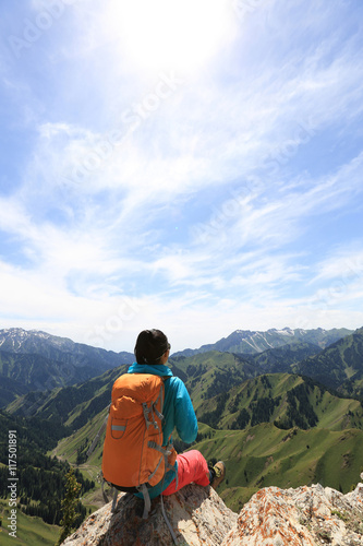 successful woman backpacker hiking on mountain peak cliff