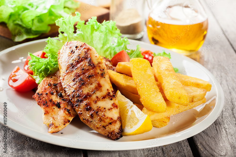 Grilled chicken breasts served with fries and fresh salad