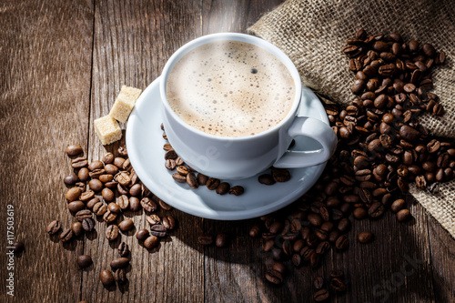 white mug of coffee beans on a wooden background