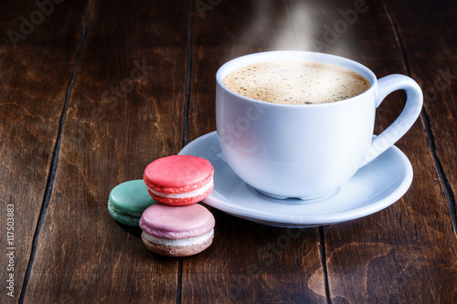 macaroon and white cup of coffee on a wooden background