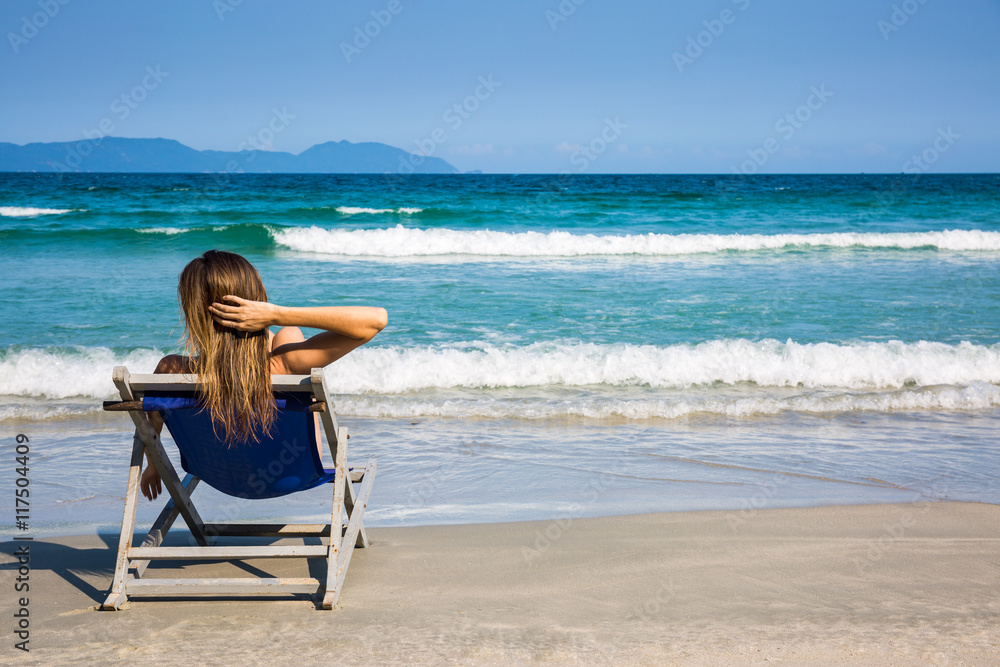 Woman on beach lounge chair relaxing with sea view