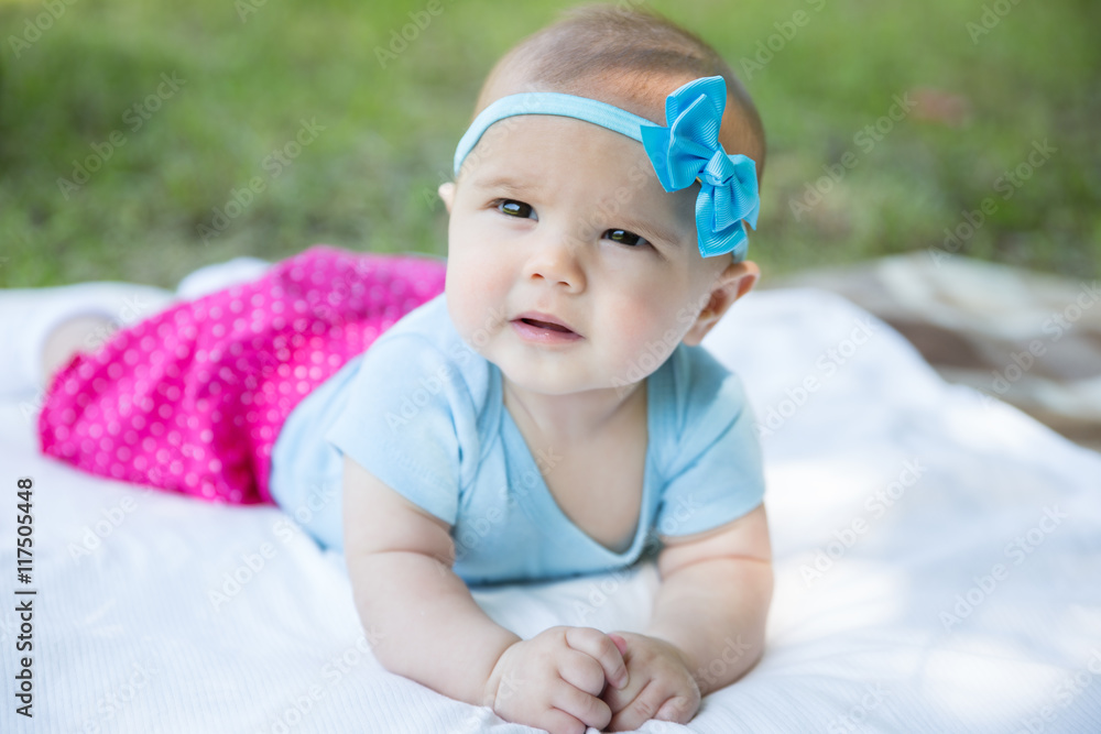 Baby girl crawling on the grass wearing blue bow Baby girl crawling on the grass wearing blue bow
