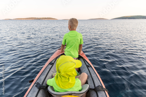 Brothers on a new adventure with father on a kayaking trip to a near by island to sleep under the stars. Concept photo of a family quality time, father and sons bond.