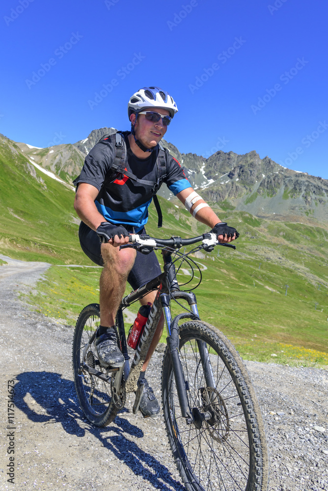 gutgelaunter Mountainbiker im Gebirge im Anstieg
