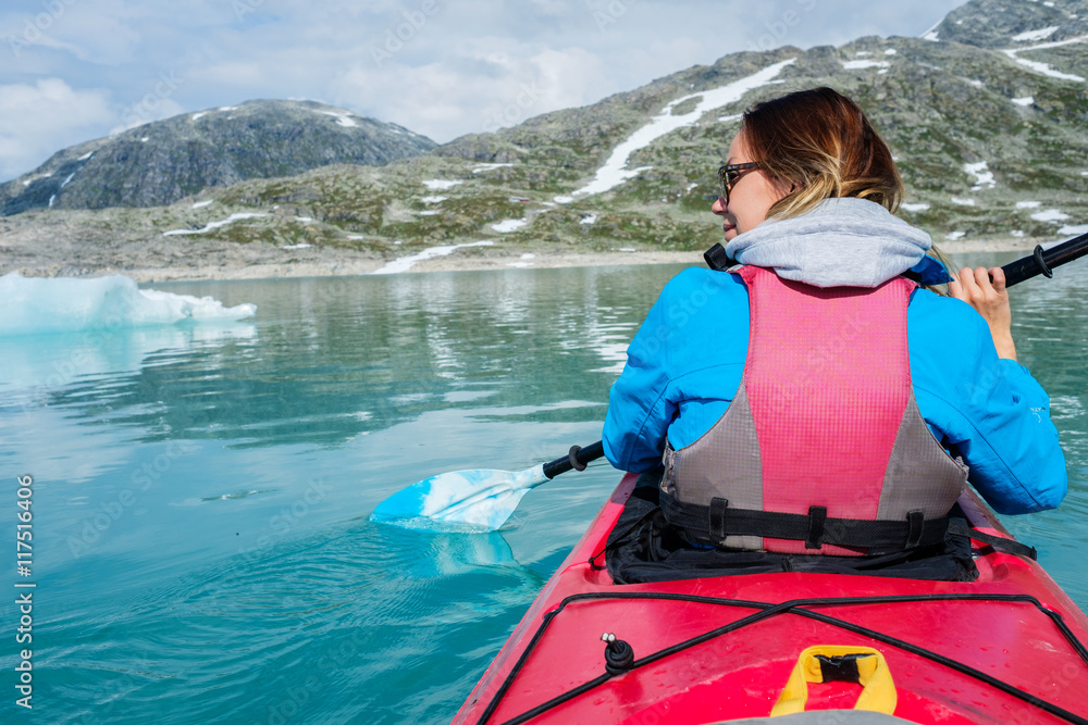 Obraz premium Woman kayaking on Styggvatnet glacier lake near Jostedalsbreen glacier.