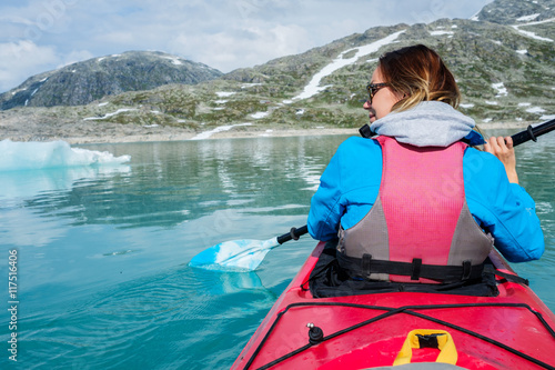 Woman kayaking on Styggvatnet glacier lake near Jostedalsbreen glacier.