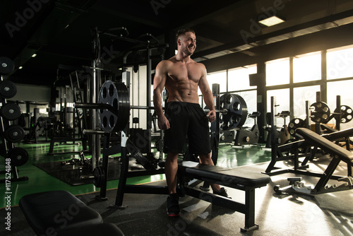 Muscular Man Flexing Muscles In Gym