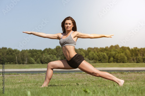 Young skinny girl does exercise on the grass.
