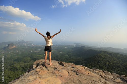 young freedom woman open arms on mountain peak