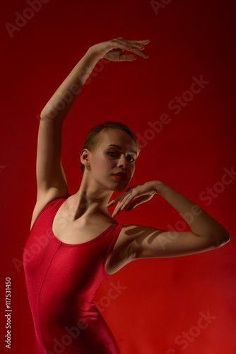 Beautiful expressive ballerina in red outfit, studio shot on red background