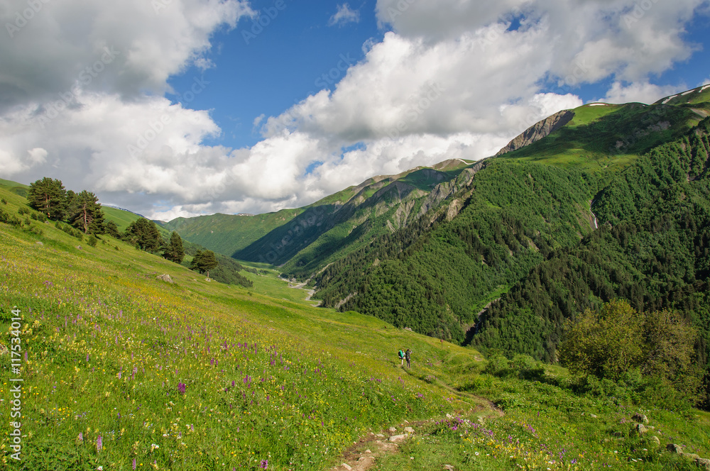 Girl with a big backpack is traveling in the Caucasus mountains, Georgia.