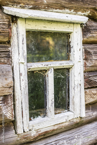 old wooden window with peeling white paint in an ancient a log cabin in the village