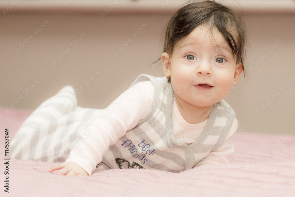 Portrait of little girl close up. Six-months old child lying on her stomach and tries to lift. Portrait of little girl close up. Six-months old child lying on her stomach and tries to lift.