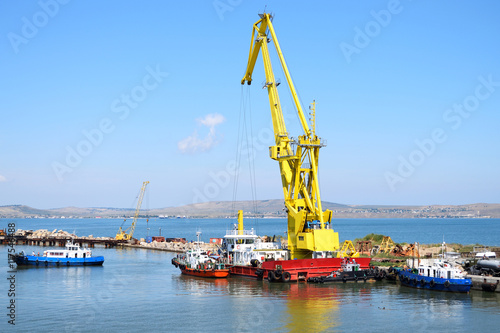 Floating crane and marine tug in the port of Russia