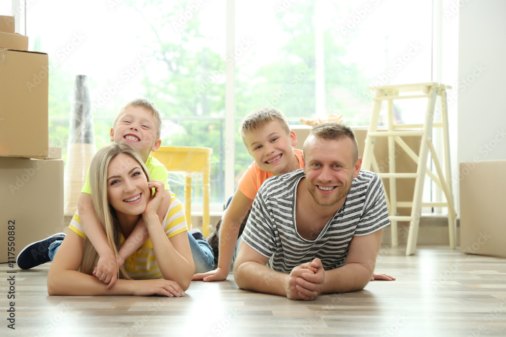 Happy family with cardboard boxes lying on wooden floor Happy family with cardboard boxes lying on wooden floor