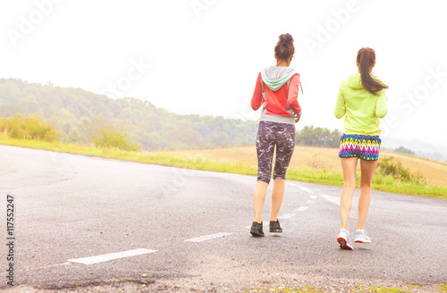 Two fit young women friends running on the road. Active healthy lifestyle and outdoor workout concept 