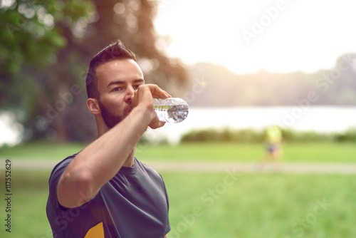 Junger Mann trinkt aus der Flasche Wasser photo