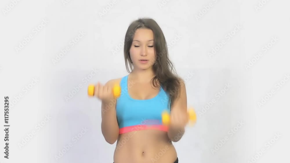 Girl doing exercises with dumbbells on a white background Girl doing exercises with dumbbells on a white background