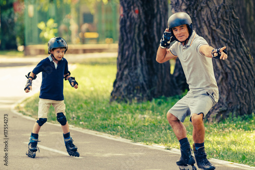 Grandfather teaching grandson roller skating in the park © Microgen