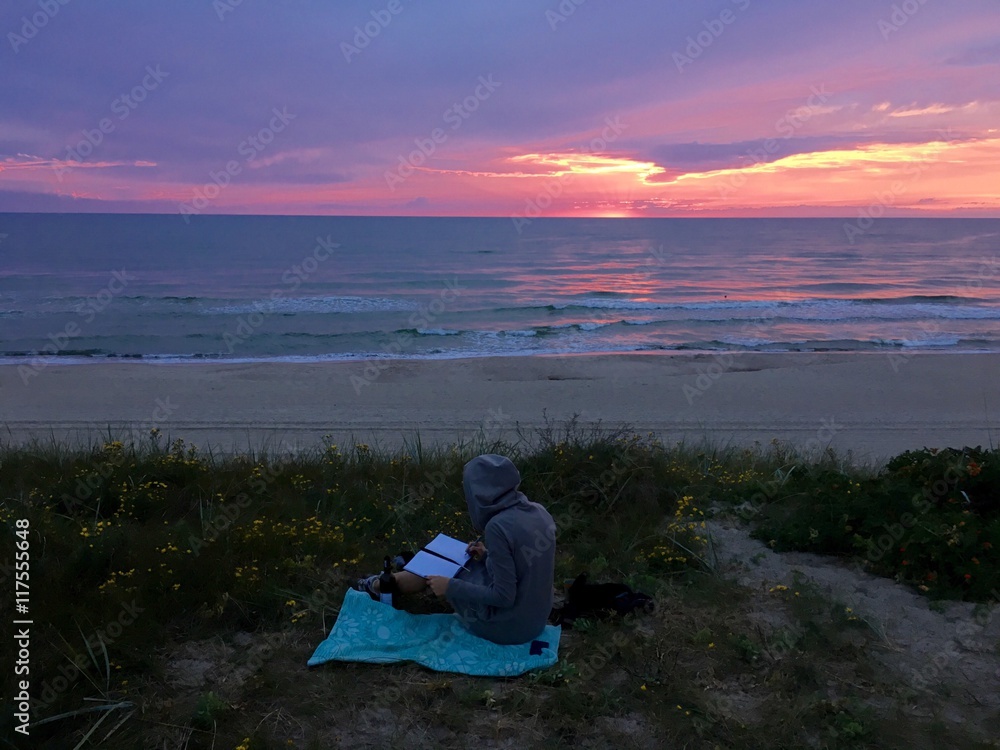 Girl sits on the beach and write in a diary