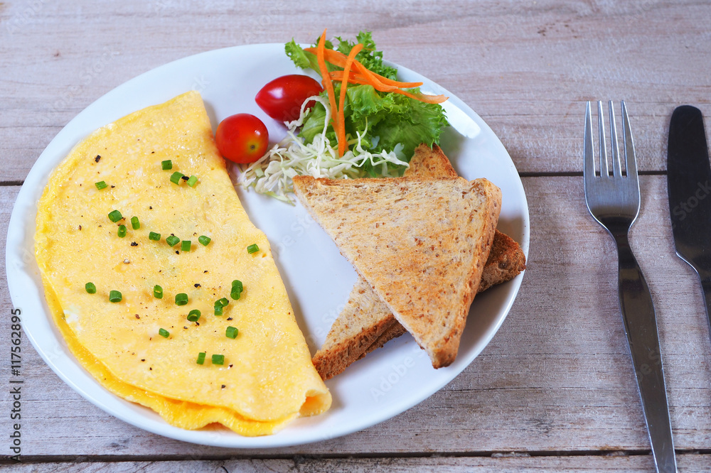 Close up of breakfast with omelette, tomatoes and and toast on a wooden table. Close up of breakfast with omelette, tomatoes and and toast on a wooden table.