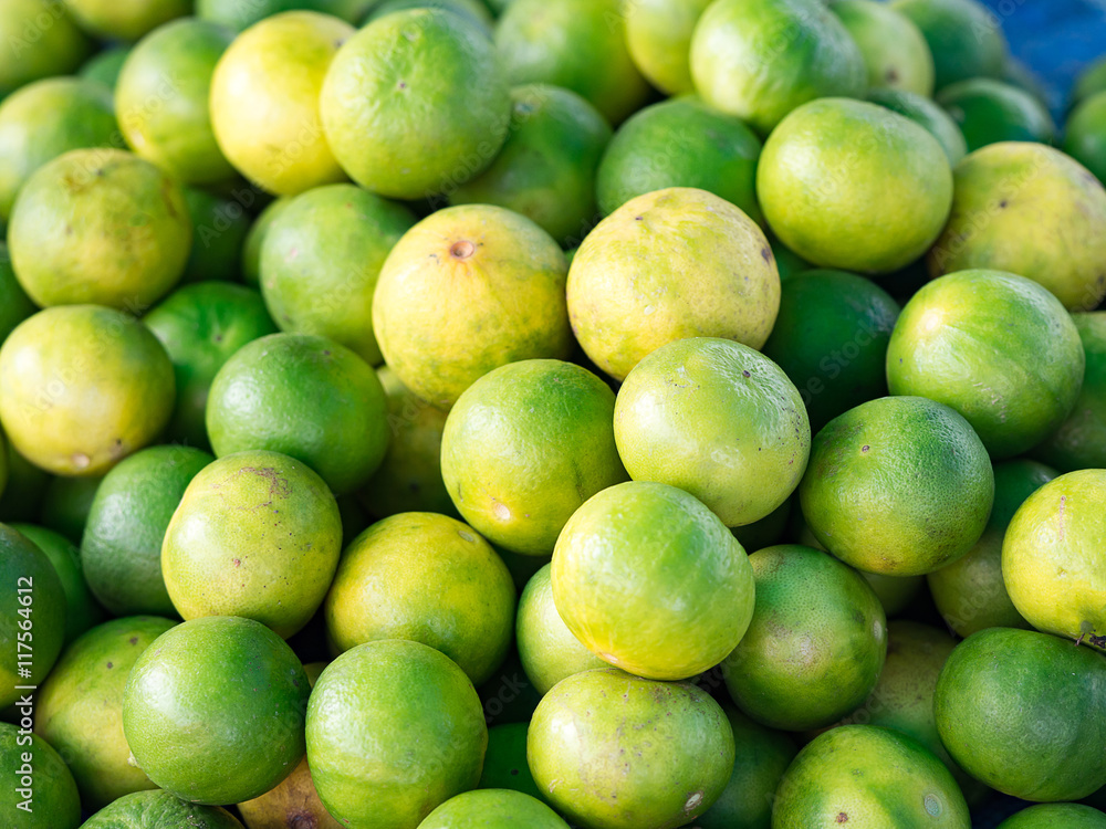 Closeup of fresh organic green lemons for retail sale in local market, Thailand (selective focus) Closeup of fresh organic green lemons for retail sale in local market, Thailand (selective focus)