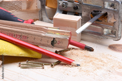 Close up of carpentry tools and electric jigsaw on wooden board
