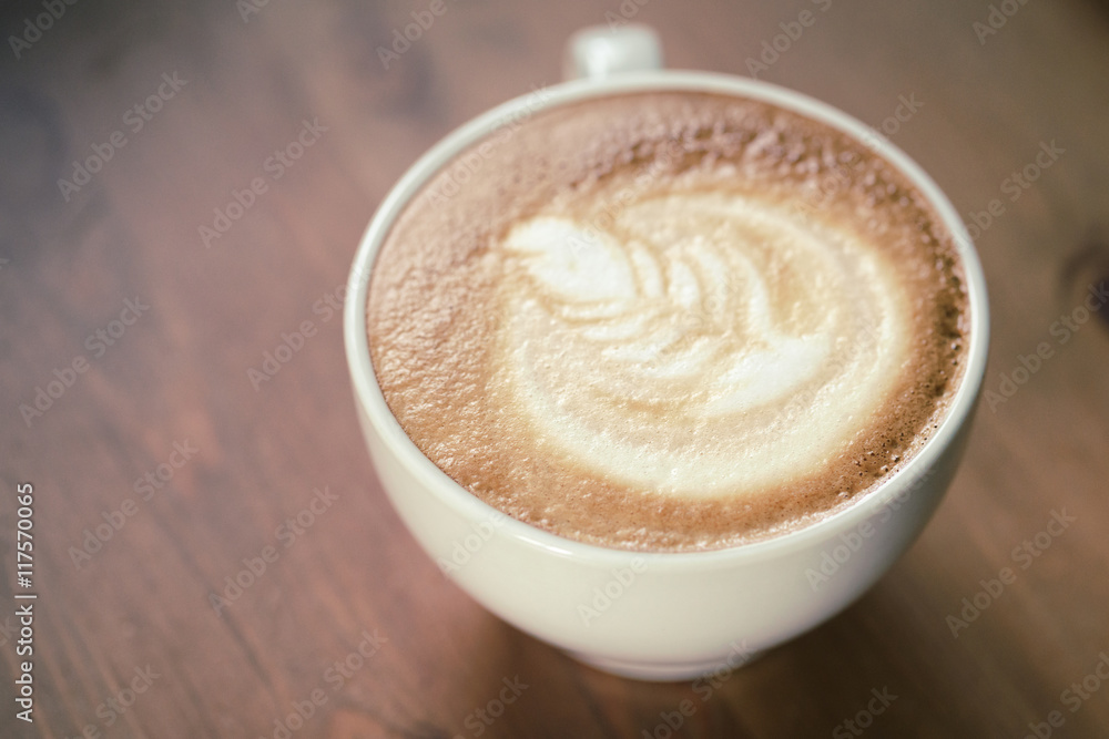 cup of cappuccino on wood table with latte art cup of cappuccino on wood table with latte art