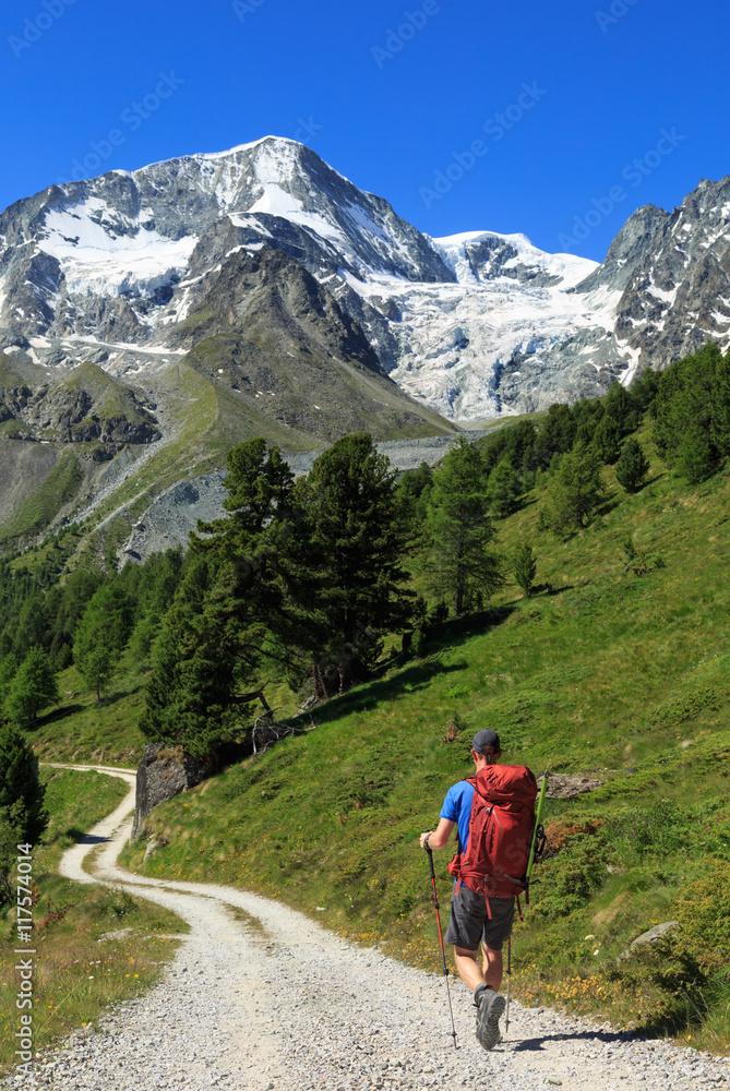 Alpinist on a gravel road on his way to the beautiful mountains of Arolla, Switzerland.