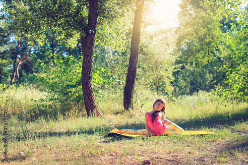 Teenager doing yoga and relaxing by siting in a grass in a park