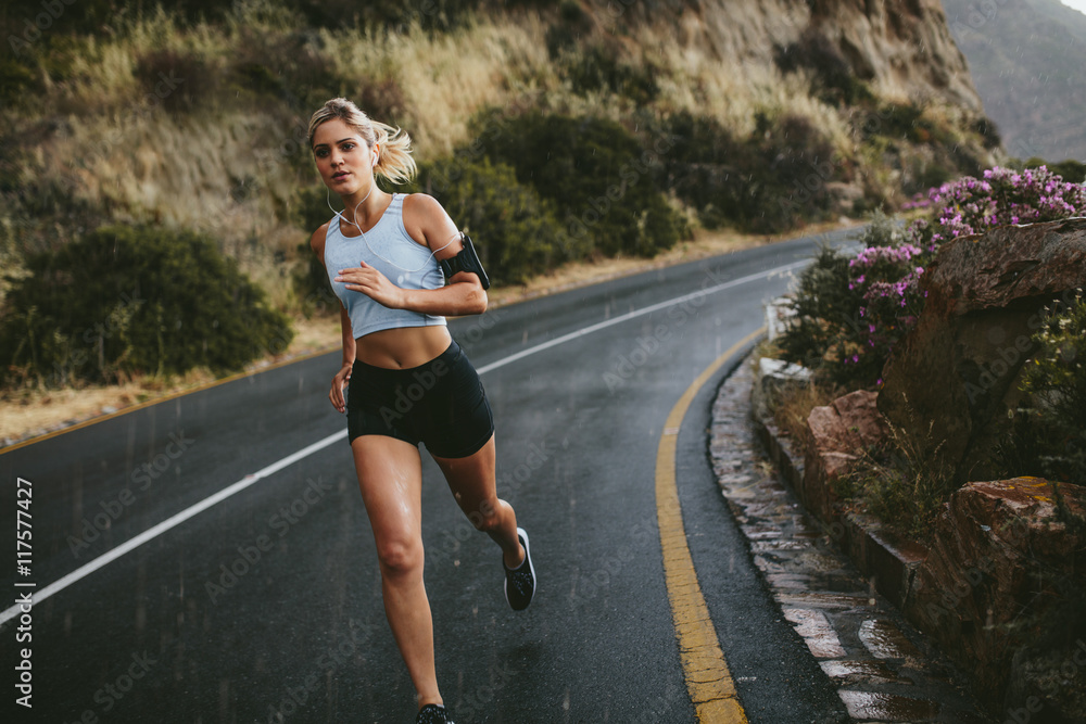 Female athlete running along the highway Female athlete running along the highway