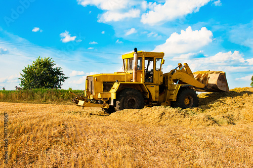 Yellow bulldozer in a field at harvest on a Sunny day