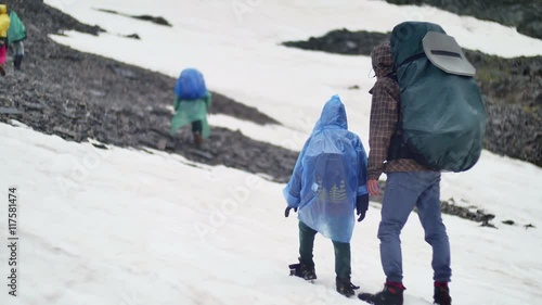 group of tourists with child carefully walk in hazardous area of high snowy mountains