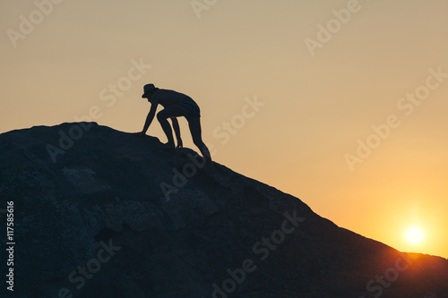 Man climbing up the hill to reach the peak in sunset © marjan4782