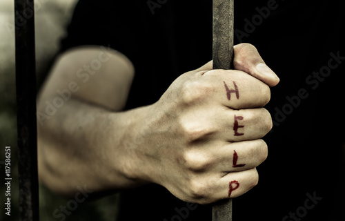 A man holds the hand of a metal rod. On the fingers is written "help."   © disha1980