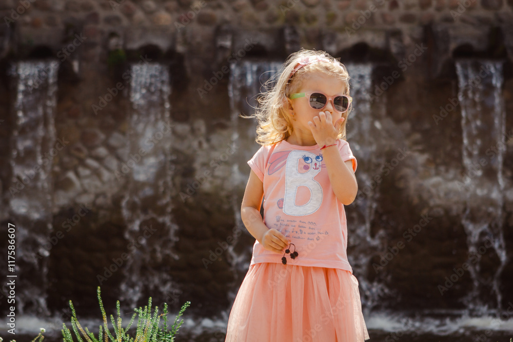 Summer portrait of a charming little 3-letnei girl in a pink dress and sunglasses. Summer portrait of a charming little 3-letnei girl in a pink dress and sunglasses.