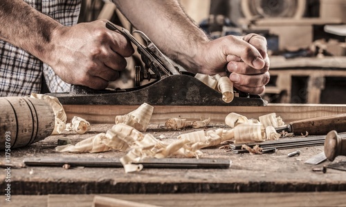 carpenter working with plane on wooden background