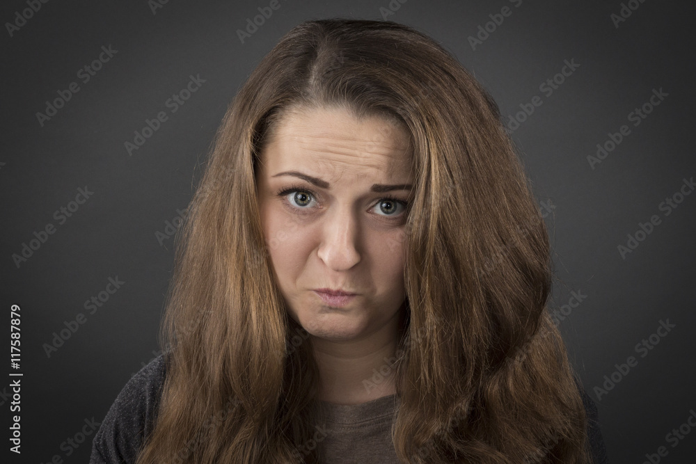 Naklejka premium Upset serious girl on a gray background 